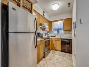 A compact kitchen with a refrigerator, stove, oven, and dishwasher. - Coastal 2BR Condo w/ Pool Access | 2 Blks to Beach (Bethany Beach)