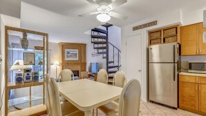 Une cuisine compacte avec un coin repas, un ventilateur de plafond, un escalier et un panneau indiquant : « Je suis à la plage ».