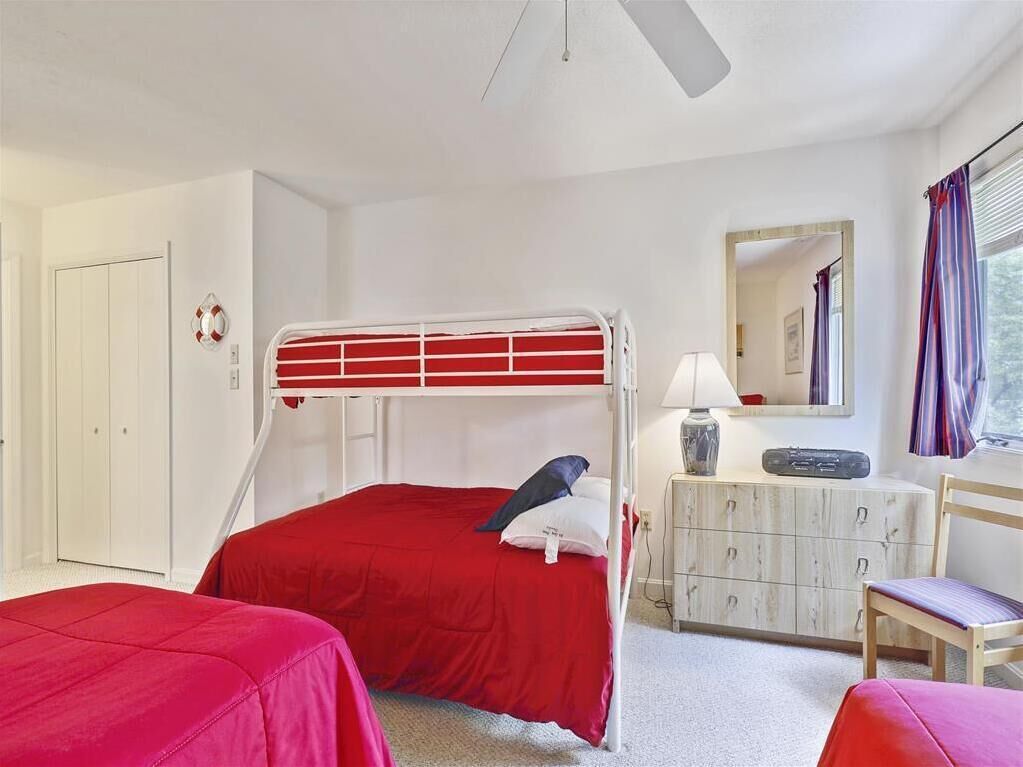 Une chambre avec un lit superposé, une commode, une chaise et un miroir.