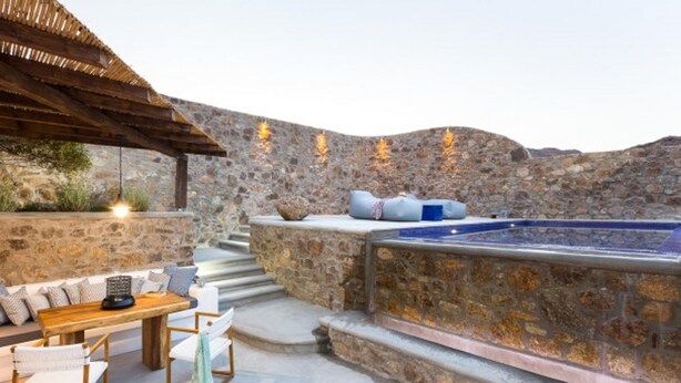 A stone-walled outdoor area with a hot tub, wooden seating, and a pergola. - Suite with Private Pool and sea view (Mykonos)
