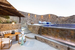 A stone-walled outdoor area with a hot tub, wooden seating, and a pergola. - Suite with Private Pool and sea view (Mykonos)