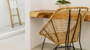 A modern interior with a round mirror on the wall, a wicker chair, a wooden table, and a ladder leaning against a glass door. - Suite with Private Pool and sea view (Mykonos)