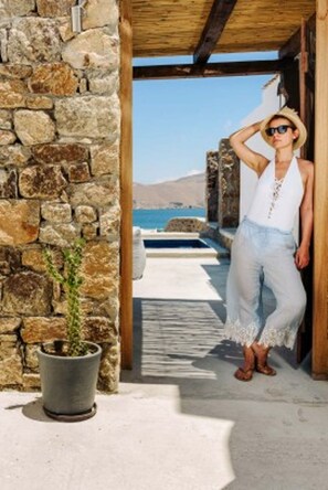 A stone wall and a wooden door leading to a pool area with a view of the sea. - Suite with Private Pool and sea view (Mykonos)