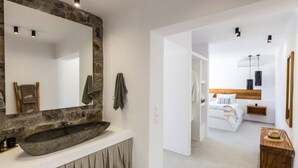 A modern bathroom with a stone sink and a large mirror. - Suite with Private Pool and sea view (Mykonos)
