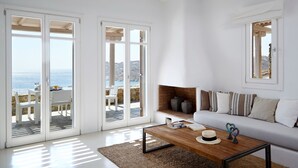 A spacious living room with a large window overlooking the sea, a white sofa, and a wooden coffee table. - Amazing view Mykonian Villa with 5 bedrooms and pool (Mykonos)