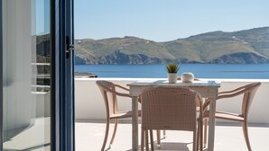 A balcony with wicker chairs and a table, overlooking a mountainous coastline. - 2 Bedroom Villa with private pool (Panormos)