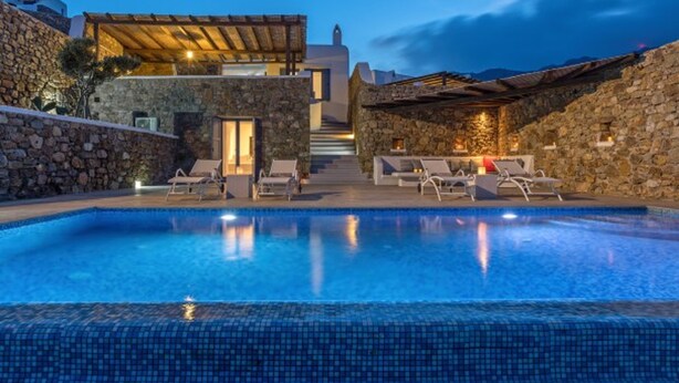 A swimming pool with lounge chairs, stone walls, and a covered area with a staircase leading to a building. - 2 Bedroom Villa with private pool (Panormos)
