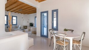 Um interior moderno com área de jantar, paredes brancas e vigas de madeira no teto.
