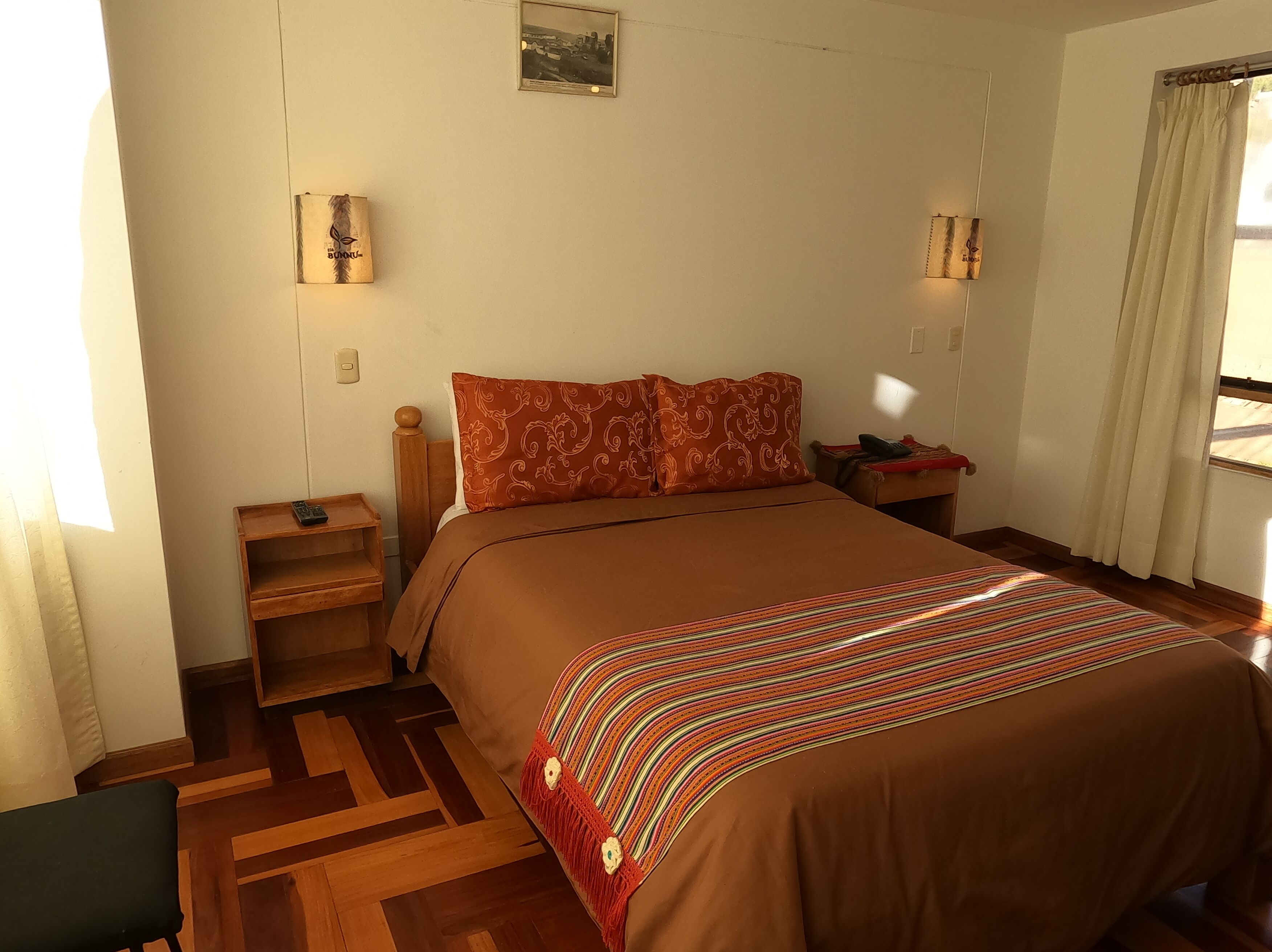 A neatly arranged bedroom with a large bed, wooden headboard, and a nightstand with a lamp.