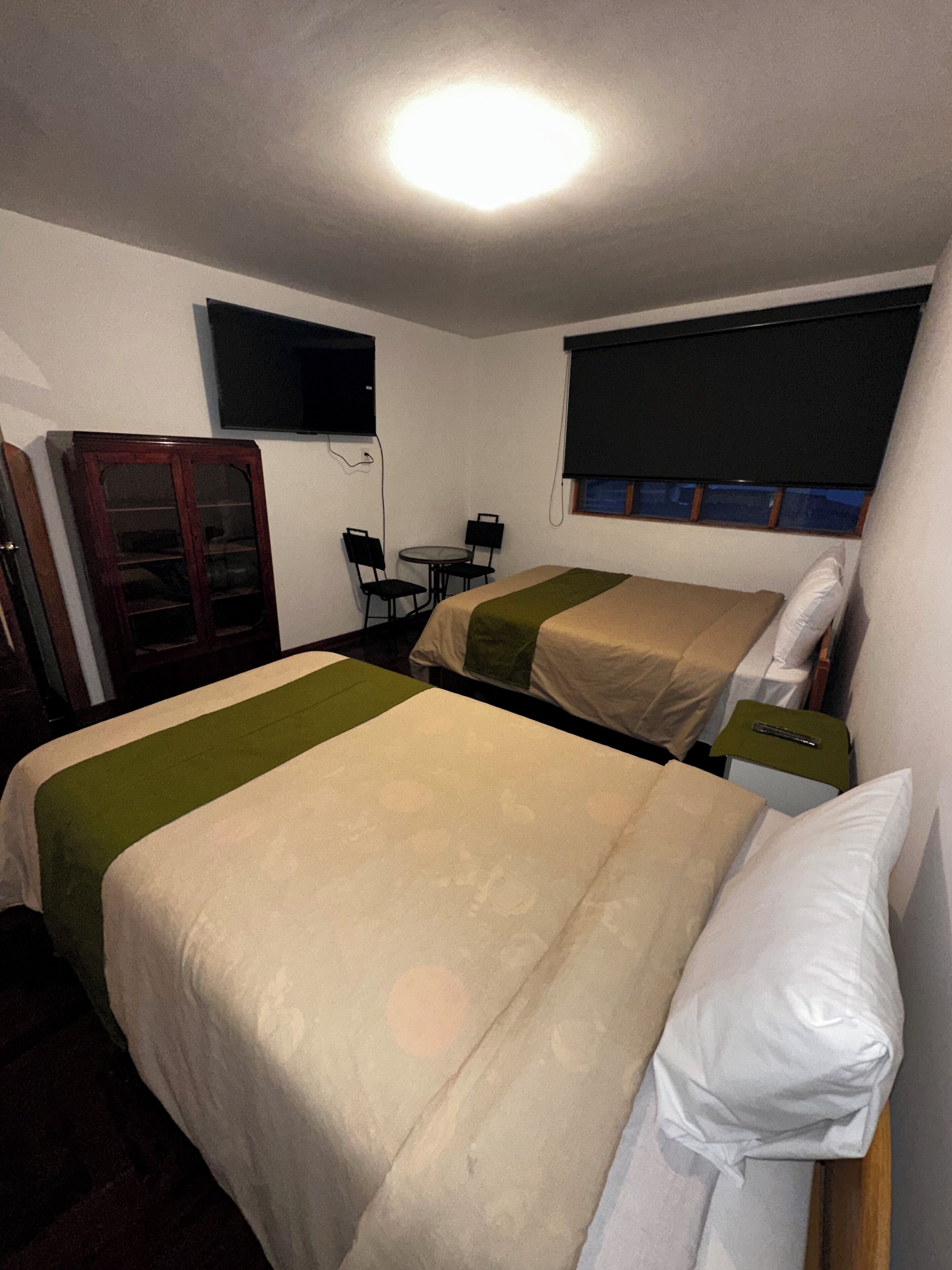 Una habitación de hotel con dos camas, un televisor, una mesita y un armario.