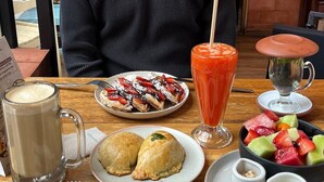 En morgenmadsopstilling med et udvalg af retter, heriblandt vafler, en frugtsalat, røræg og et glas juice.