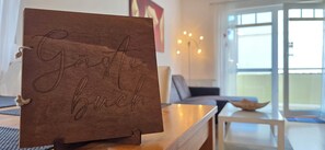 A wooden sign with the text 'Gäste buch' on a stand in a room with a sofa, a lamp, and a window. - Beachfront apartment, 2-room unit on the 1st floor with Wi-Fi (Graal-Müritz)