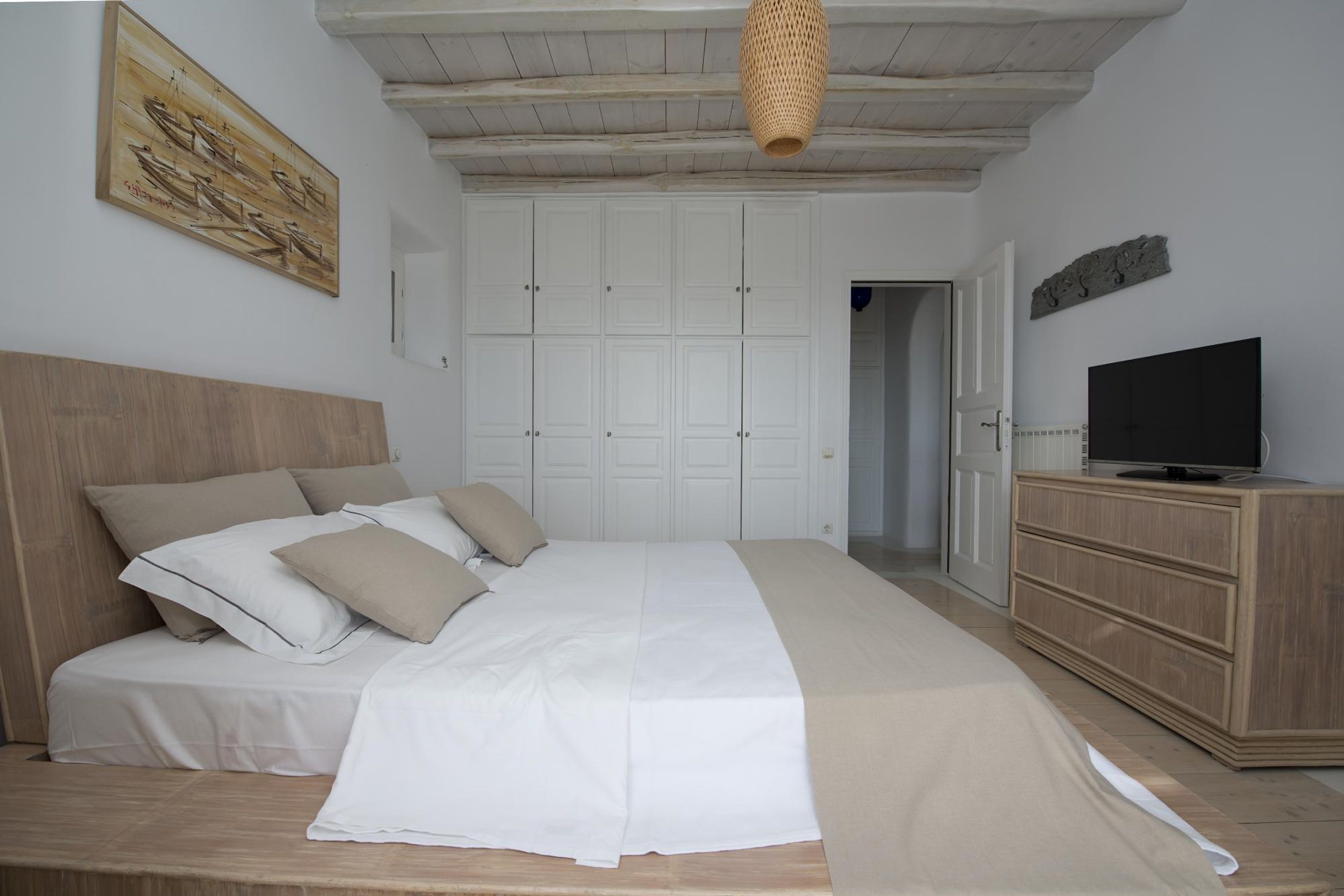 Un dormitorio con una cama grande, un armario, un televisor y un cuadro en la pared.