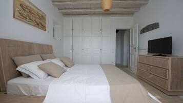 Un dormitorio con una cama grande, un armario, un televisor y un cuadro en la pared.