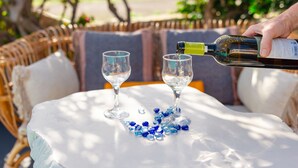 A table with two wine glasses and a bottle being poured into one. - Daphne - Two Bedroom Villa, private pool, sea view (Agia Paraskevi)