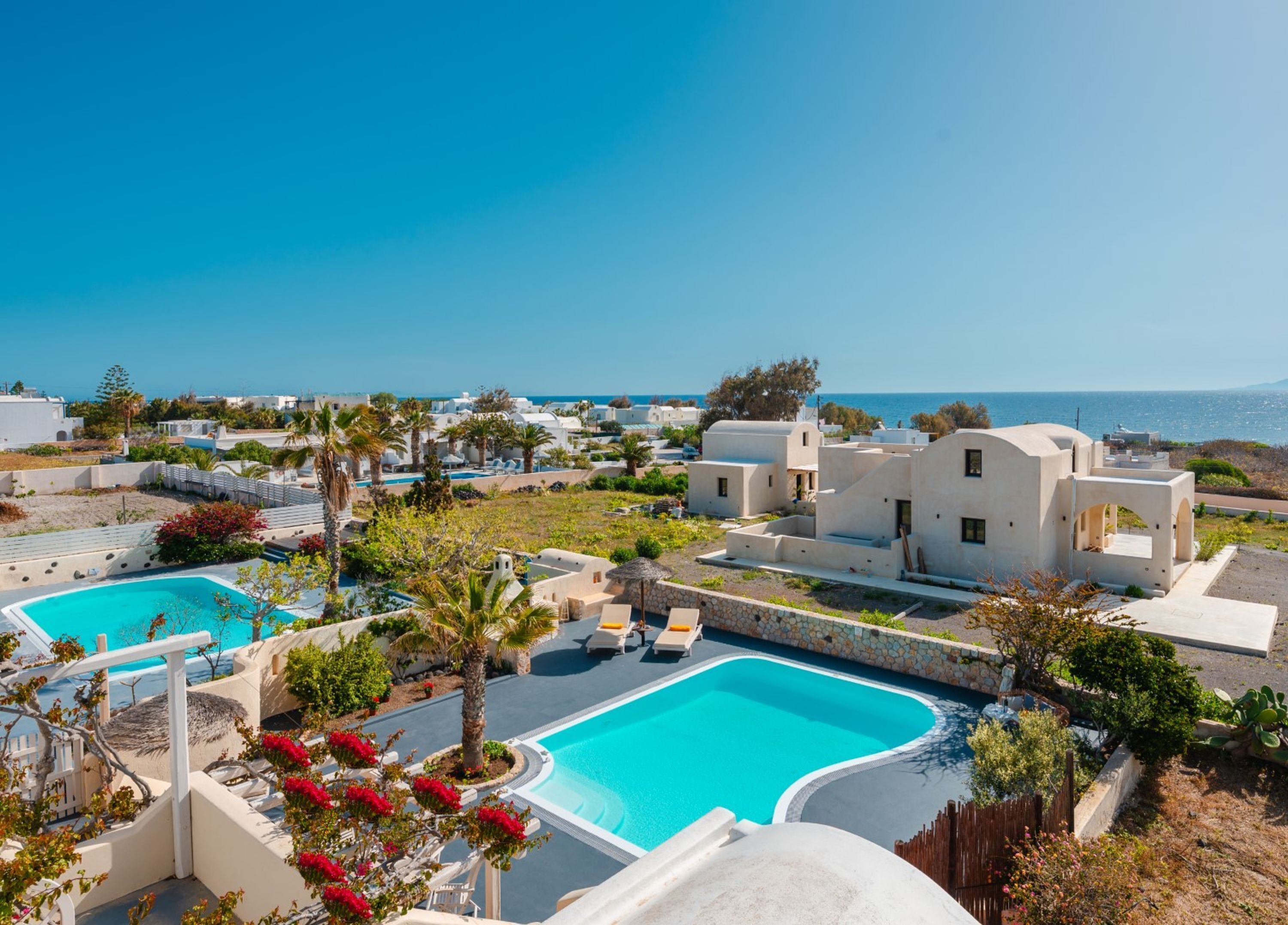 Un resort con varias piscinas, edificios blancos y vista al mar.