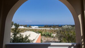 A view through an arched window overlooking a coastal landscape with buildings and vegetation. - Daphne - Two Bedroom Villa, private pool, sea view (Agia Paraskevi)