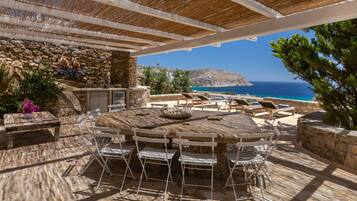 An outdoor dining area with a stone wall, a round table, and chairs.