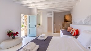 A modern bedroom with a large bed, a seating area, and a view of the outdoors. - Rocky Mansion Mykonos (Mykonos)
