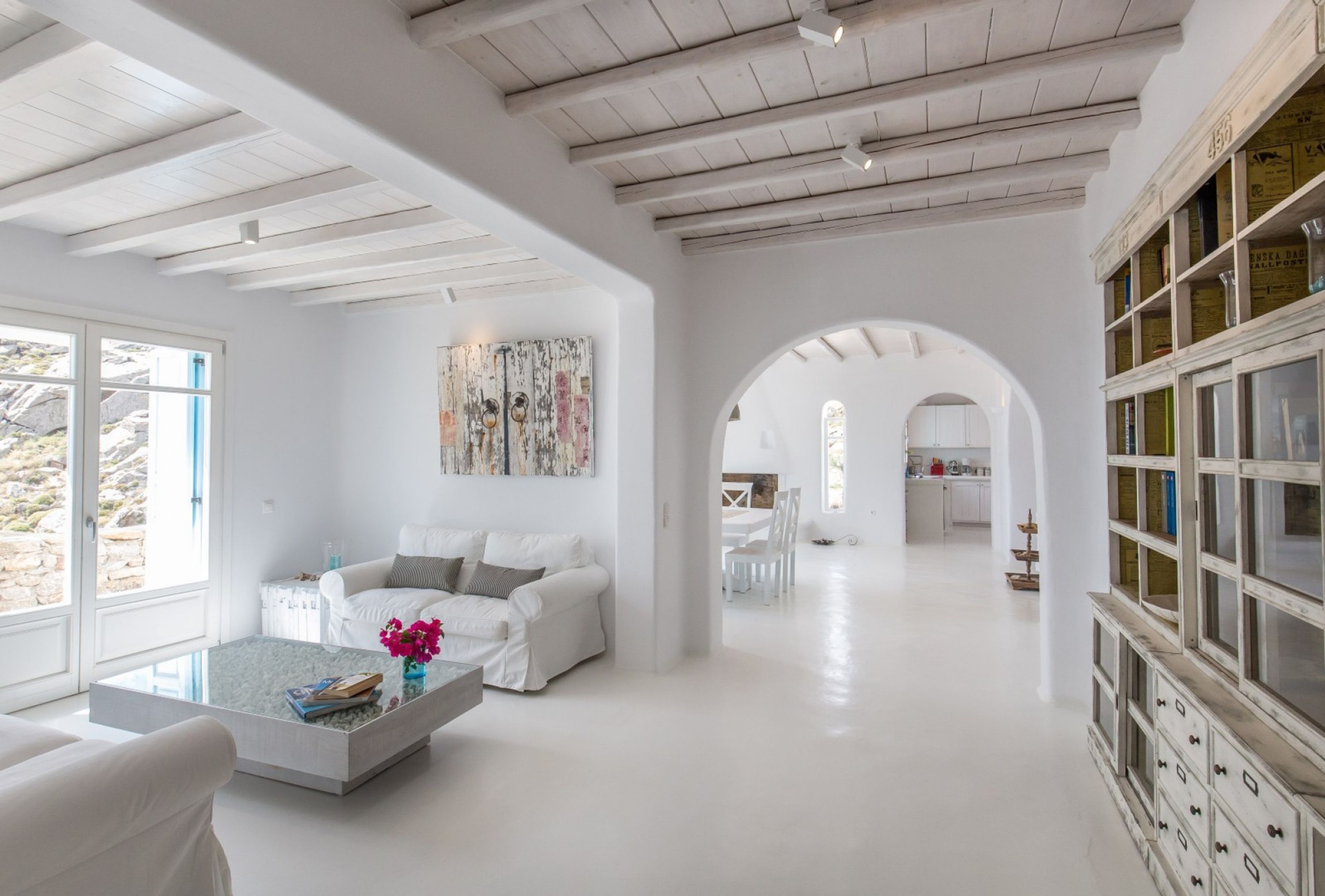A spacious, modern living room with a white sofa, a coffee table, and a bookshelf.