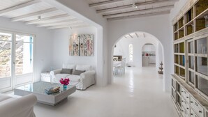 A spacious, modern living room with a white sofa, a coffee table, and a bookshelf. - Rocky Mansion Mykonos (Mykonos)