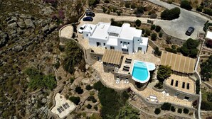 An aerial view of a modern villa with a swimming pool, multiple cars, and a rocky landscape. - Rocky Mansion Mykonos (Mykonos)