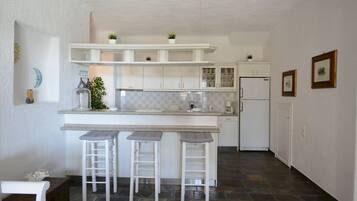 Una cocina moderna con armarios blancos, una isla central con taburetes, un refrigerador y un microondas.