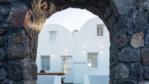 Un arco in pietra che conduce a un edificio bianco con una scala e una barriera di corda.