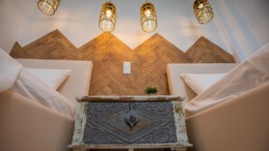 Una habitación con una pared de madera, un cofre decorativo y tres lámparas colgantes.