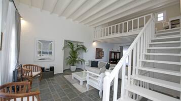 Amplia sala de estar con una escalera blanca, muebles de madera y una planta grande en maceta.