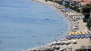 A coastal beach with numerous umbrellas and sun loungers, indicating a beachside resort area.