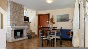 A dining area with a stone fireplace, a blue sofa, and a painting on the wall.