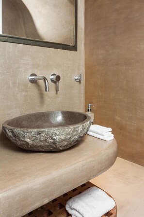 Une salle de bain avec un lavabo en pierre, un miroir et un porte-serviettes.