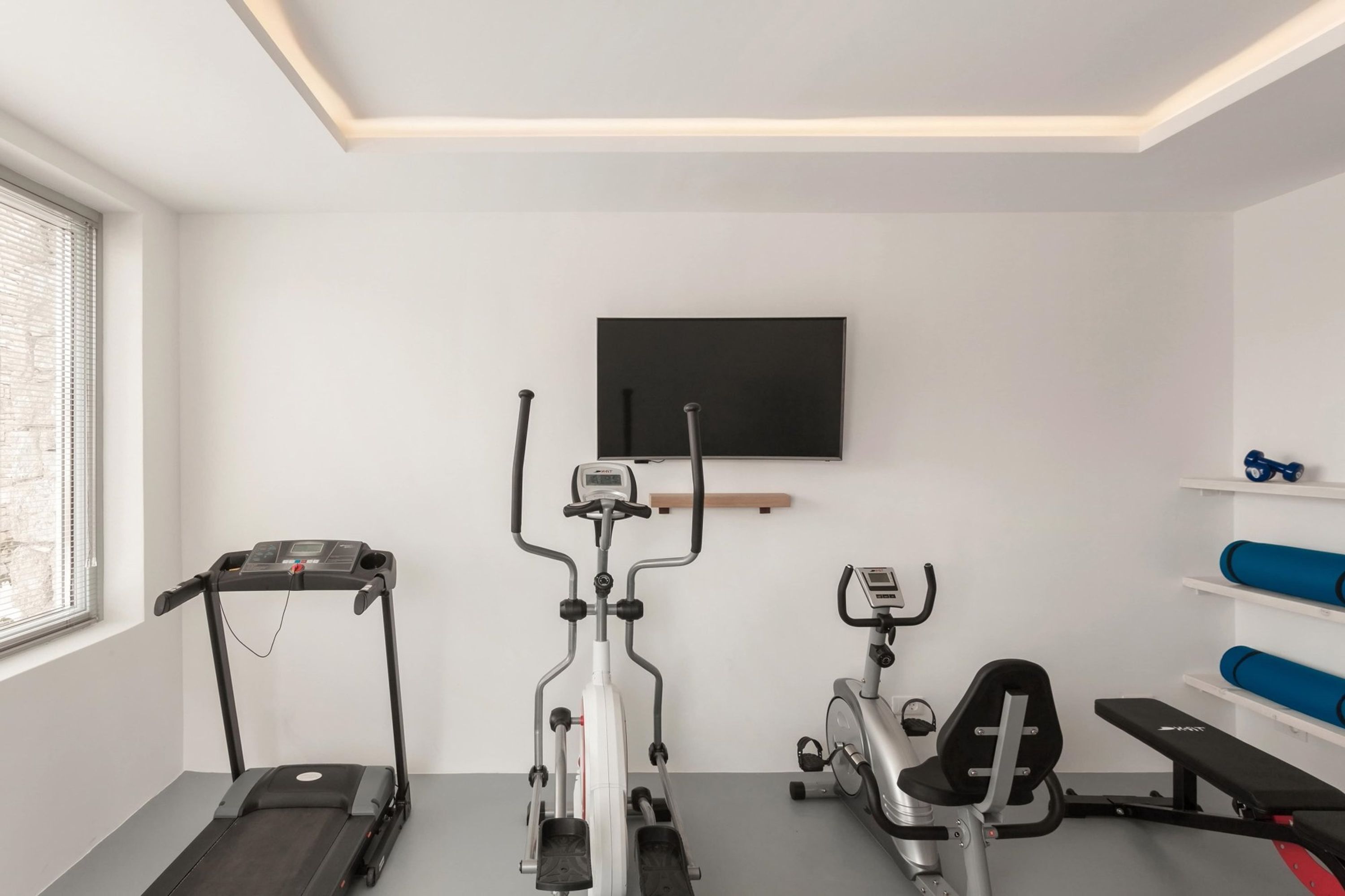 A modern home gym with a treadmill, elliptical, and stationary bike.