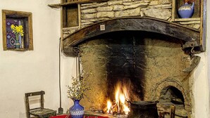 Una habitación rústica con chimenea de piedra, muebles de madera y una alfombra colorida.