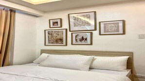 Una habitación de hotel con una cama, cabecero y cuatro cuadros en la pared.