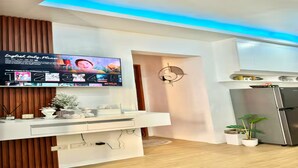 Una cocina moderna con televisión integrada mostrando una lista de películas, un refrigerador y un adorno de pared decorativo.