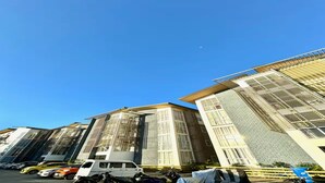 Un edificio moderno con amplias ventanas y un estacionamiento con varios vehículos.