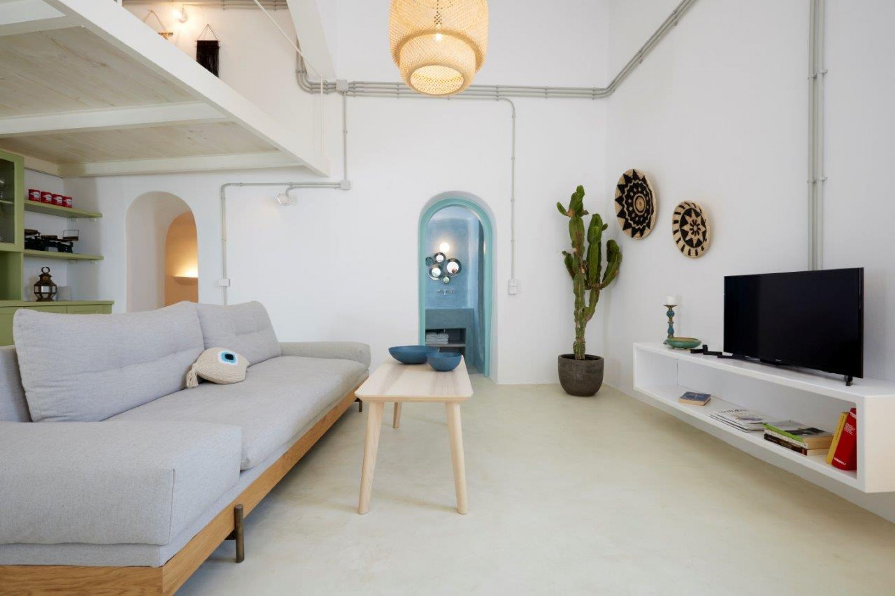 Una sala de estar moderna con un sofá, una mesita, un televisor y elementos decorativos.