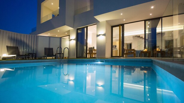 A modern pool area with clear glass walls, a well-lit interior, and a contemporary design. - Opulent VILLA K on Crete (Galatas)
