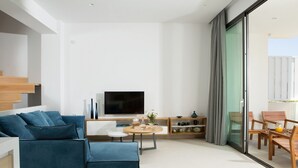 A modern living room with a sofa, TV, coffee table, and a dining area with chairs and a table. - Opulent VILLA K on Crete (Galatas)