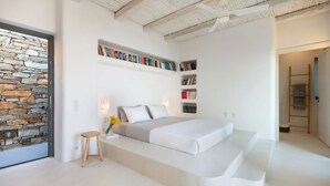 Un dormitorio moderno con una pared de piedra, una cama con base de madera y estanterías empotradas.