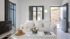 Un salón moderno con un sofá blanco, un televisor y una mesa de centro con un sombrero y flores.