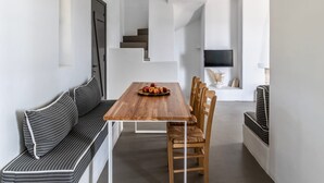 A modern dining area with a wooden table, striped bench seating, and a staircase leading to another room. - Sky 3 Bedroom Villa Sea View Private Pool (Kolympithres)