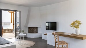Ein modernes Wohnzimmer mit Kamin, Fernseher und Meerblick.