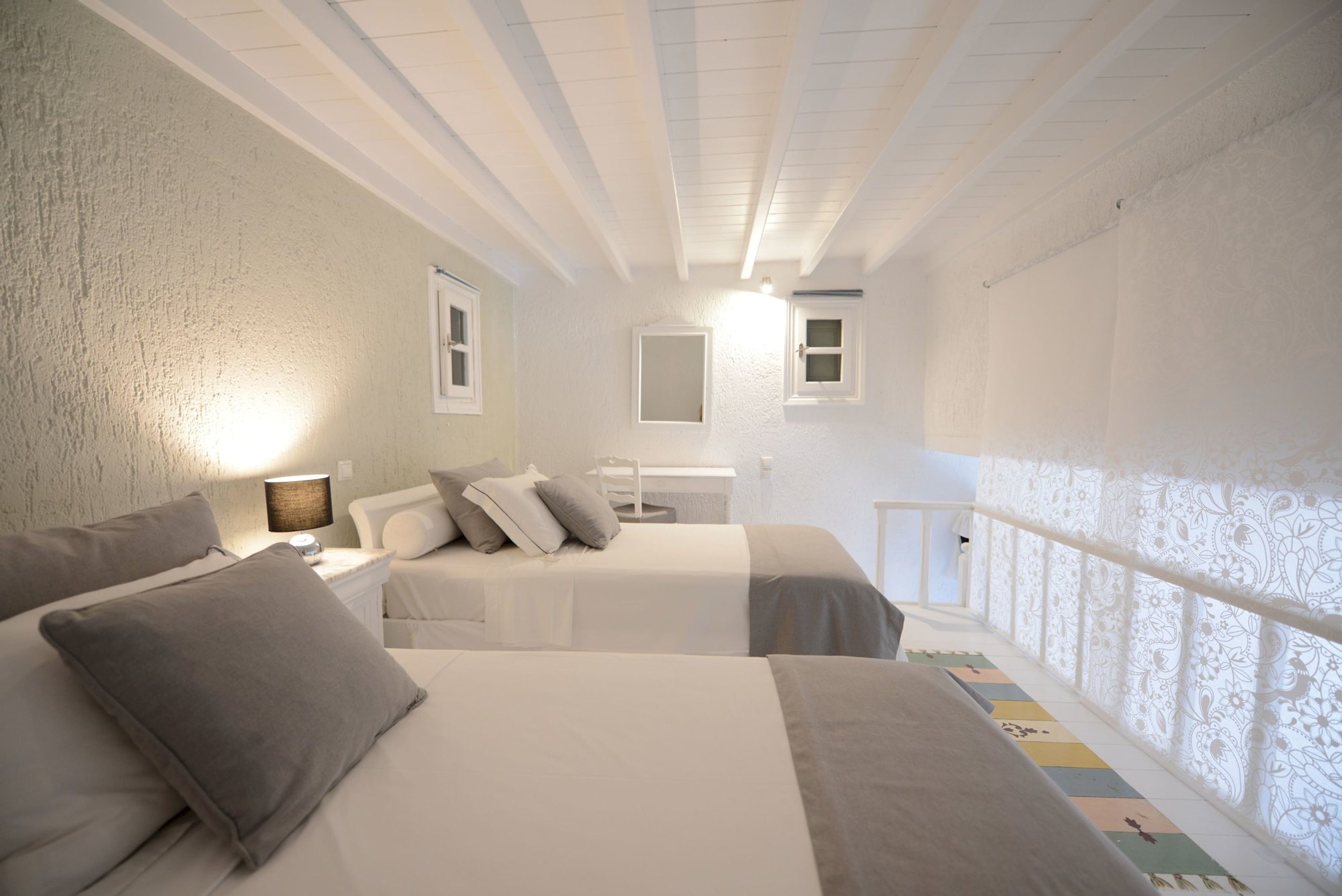 Un dormitorio con dos camas, una mesita de noche, una lámpara y una ventana con vistas.