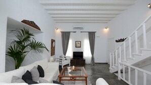A living room with a white sofa, a coffee table, a TV, and a staircase. - Villa Fragkia/private lounge area, sea view (Kalafatis)