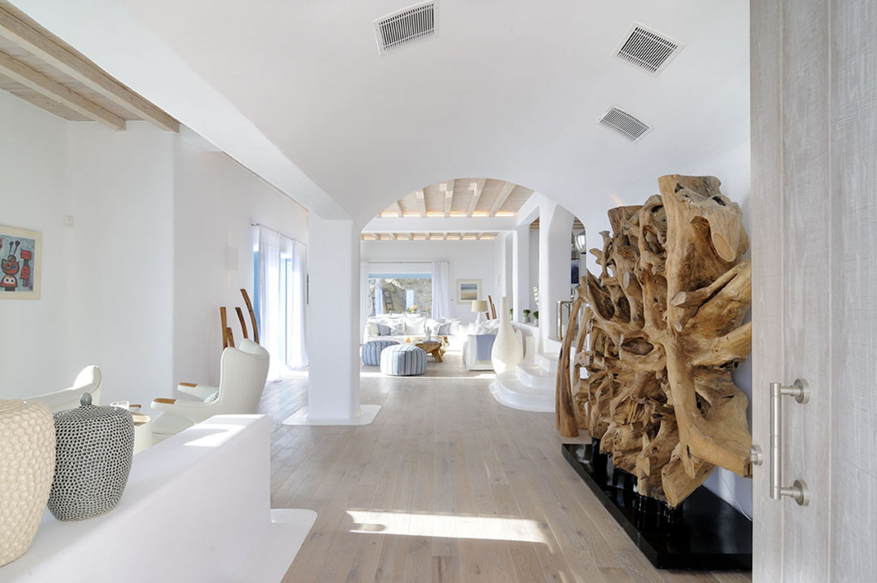 Un ambiente spazioso e moderno con pavimento in legno, arredi bianchi e un'ampia scultura in legno.