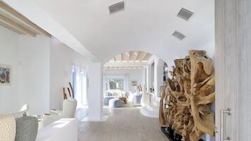 Un ambiente spazioso e moderno con pavimento in legno, arredi bianchi e un'ampia scultura in legno.