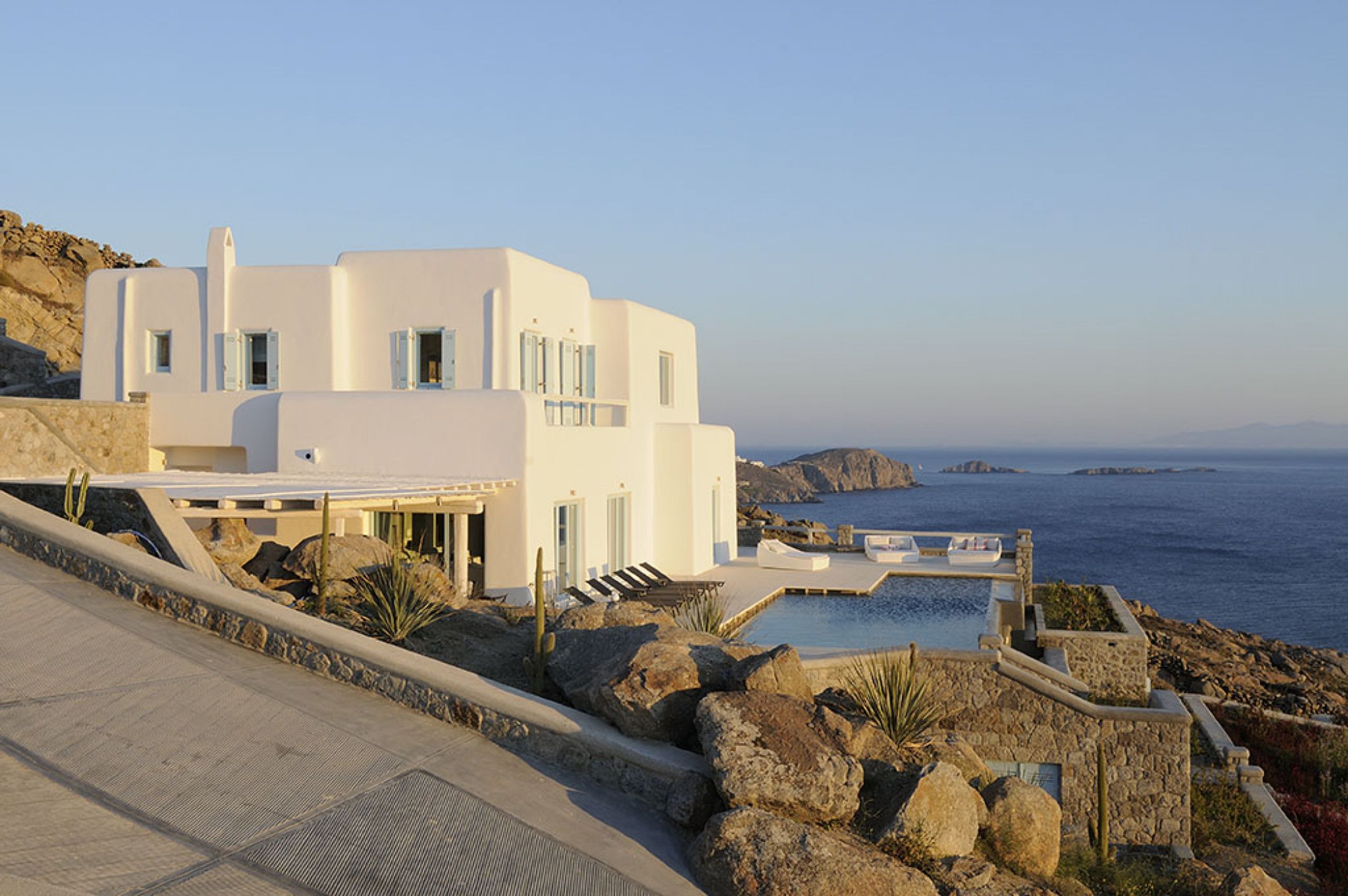 Un edificio moderno e bianco con piscina e vista sul mare.
